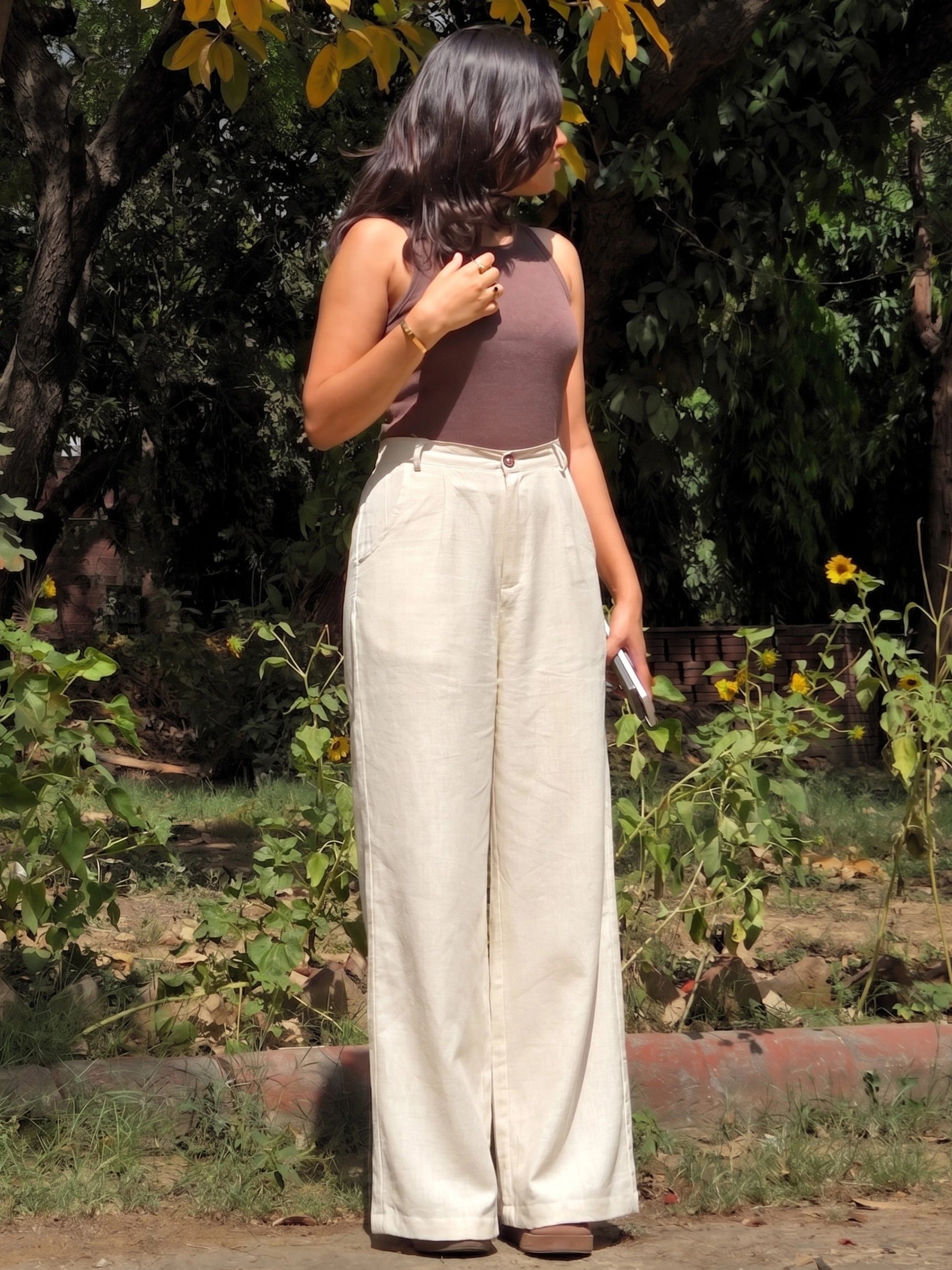 Side angle of flowing wide leg beige cotton linen trousers showing the relaxed, loose fit.