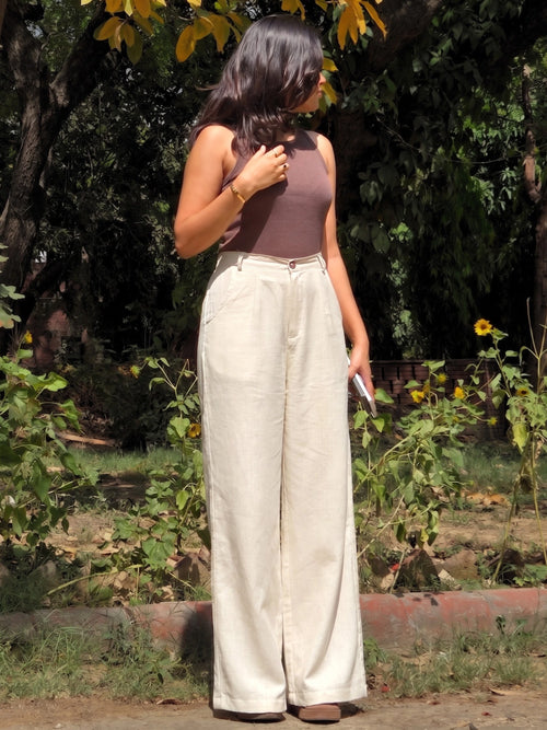 Side angle of flowing wide leg beige cotton linen trousers showing the relaxed, loose fit.