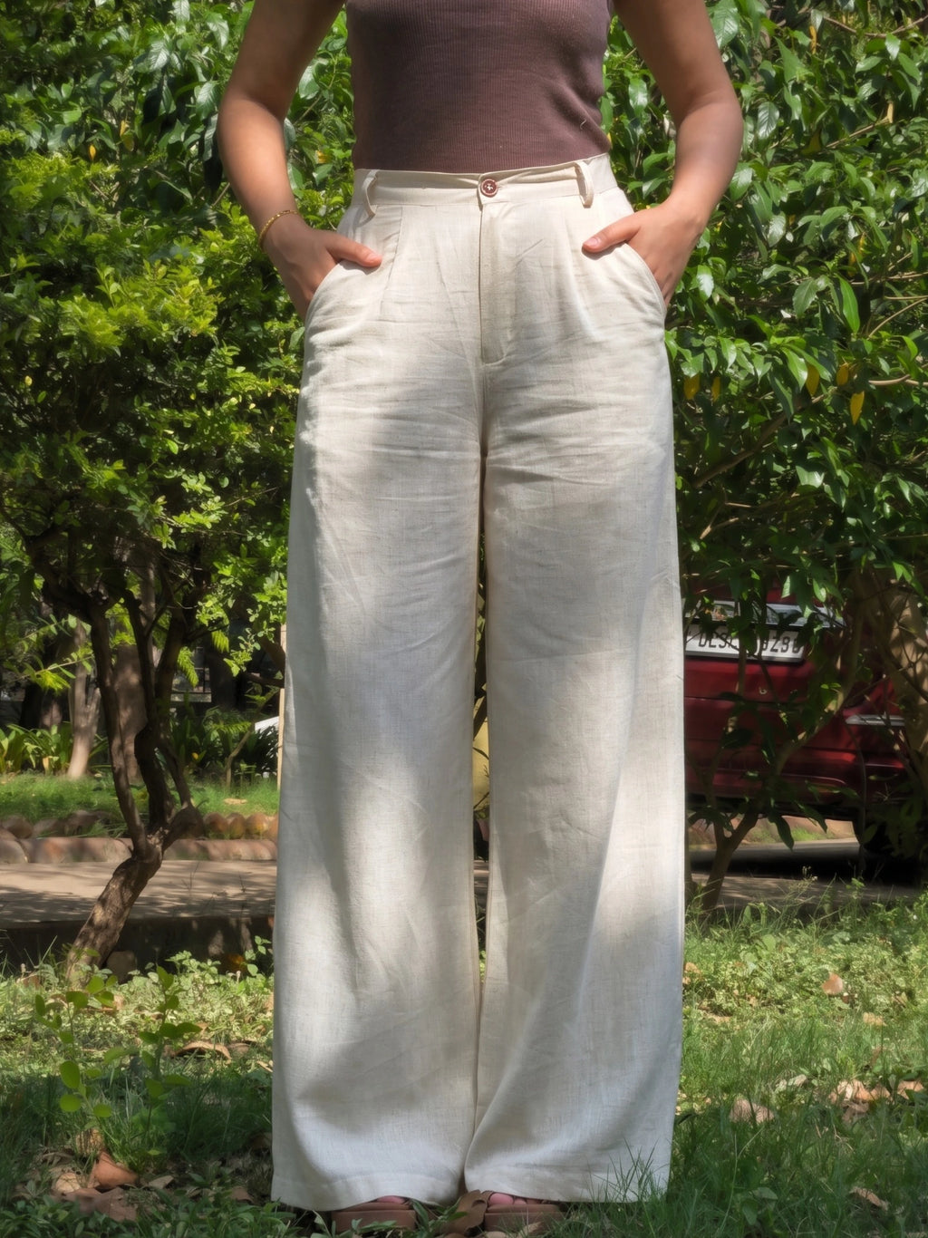 Model posing from behind in high waisted wide leg beige trousers.