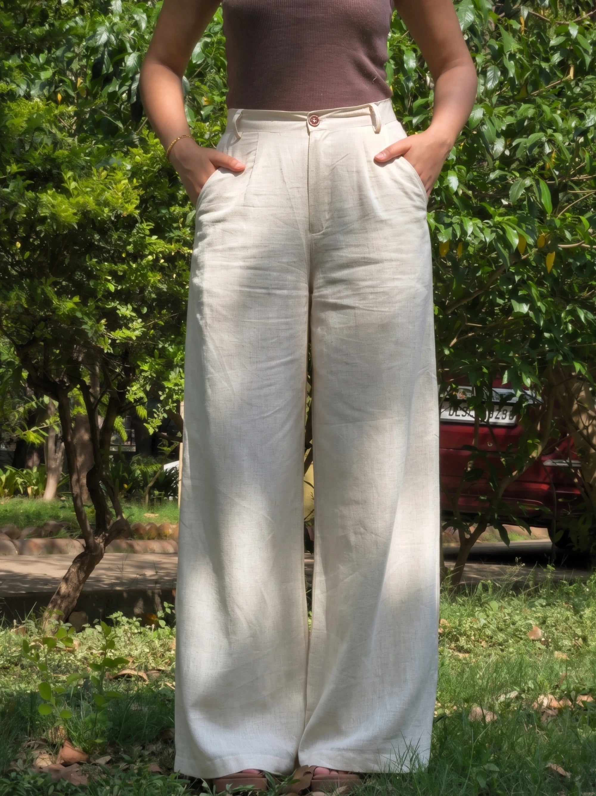 Model posing from behind in high waisted wide leg beige trousers.