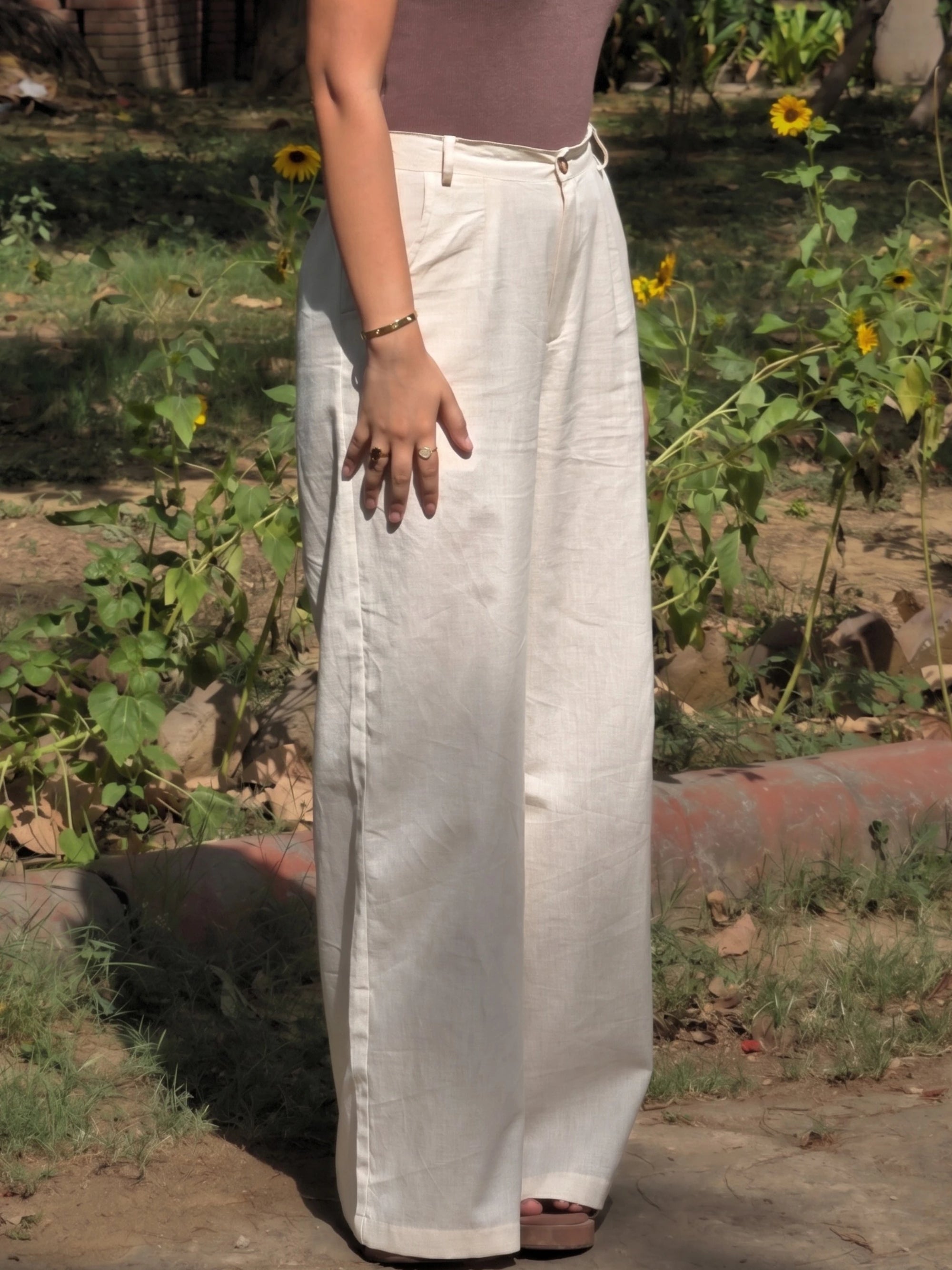 Casual daytime styling of long wide leg beige cotton pants paired with sandals.