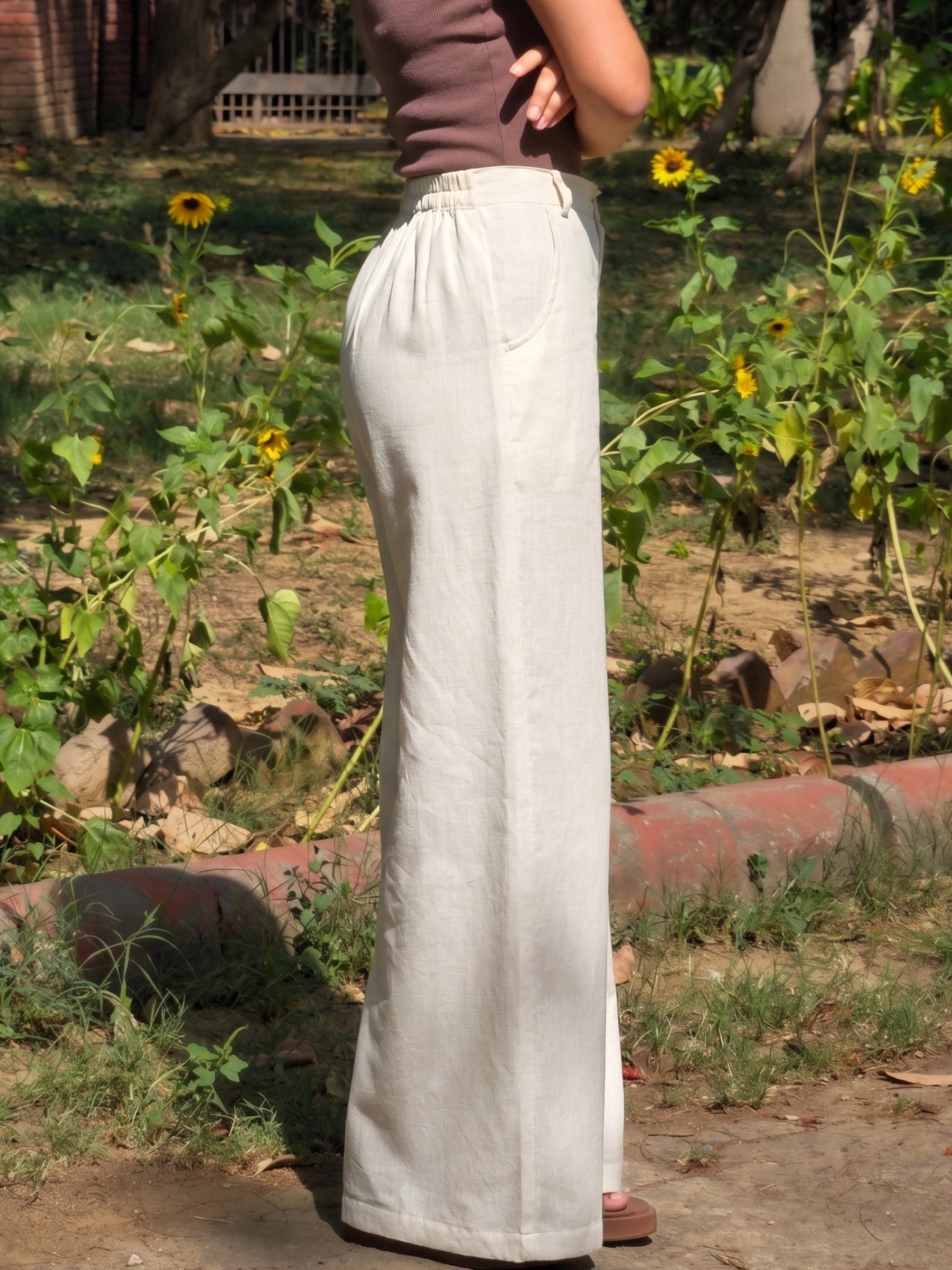 Close-up of the single button and zip closure on the beige cotton linen flax pants.
