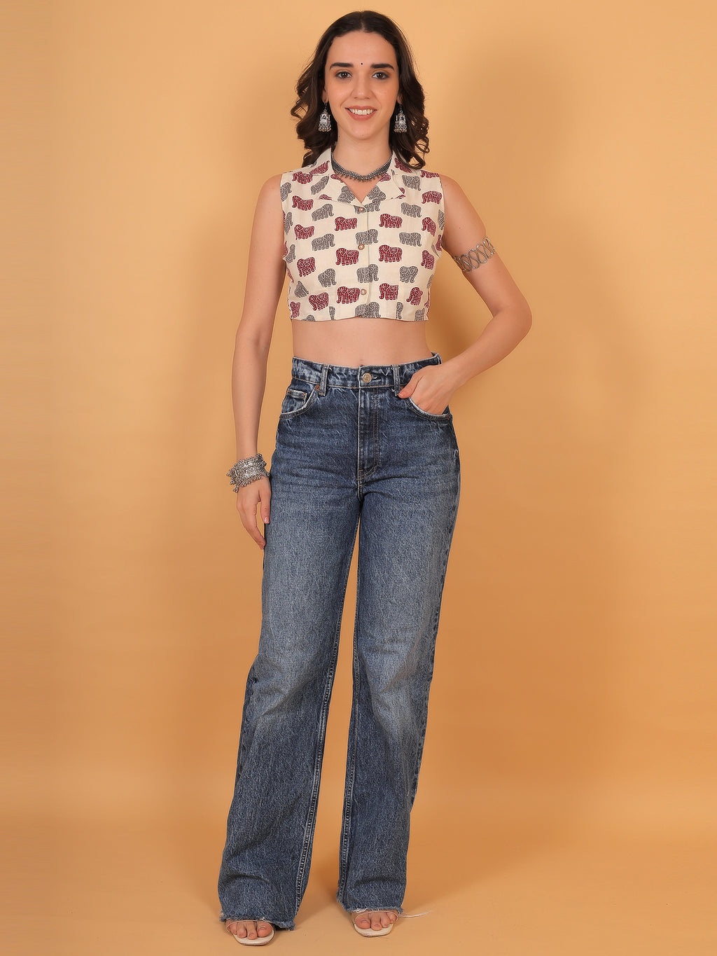 Woman wearing collared ethnic crop top paired with high-waisted blue jeans