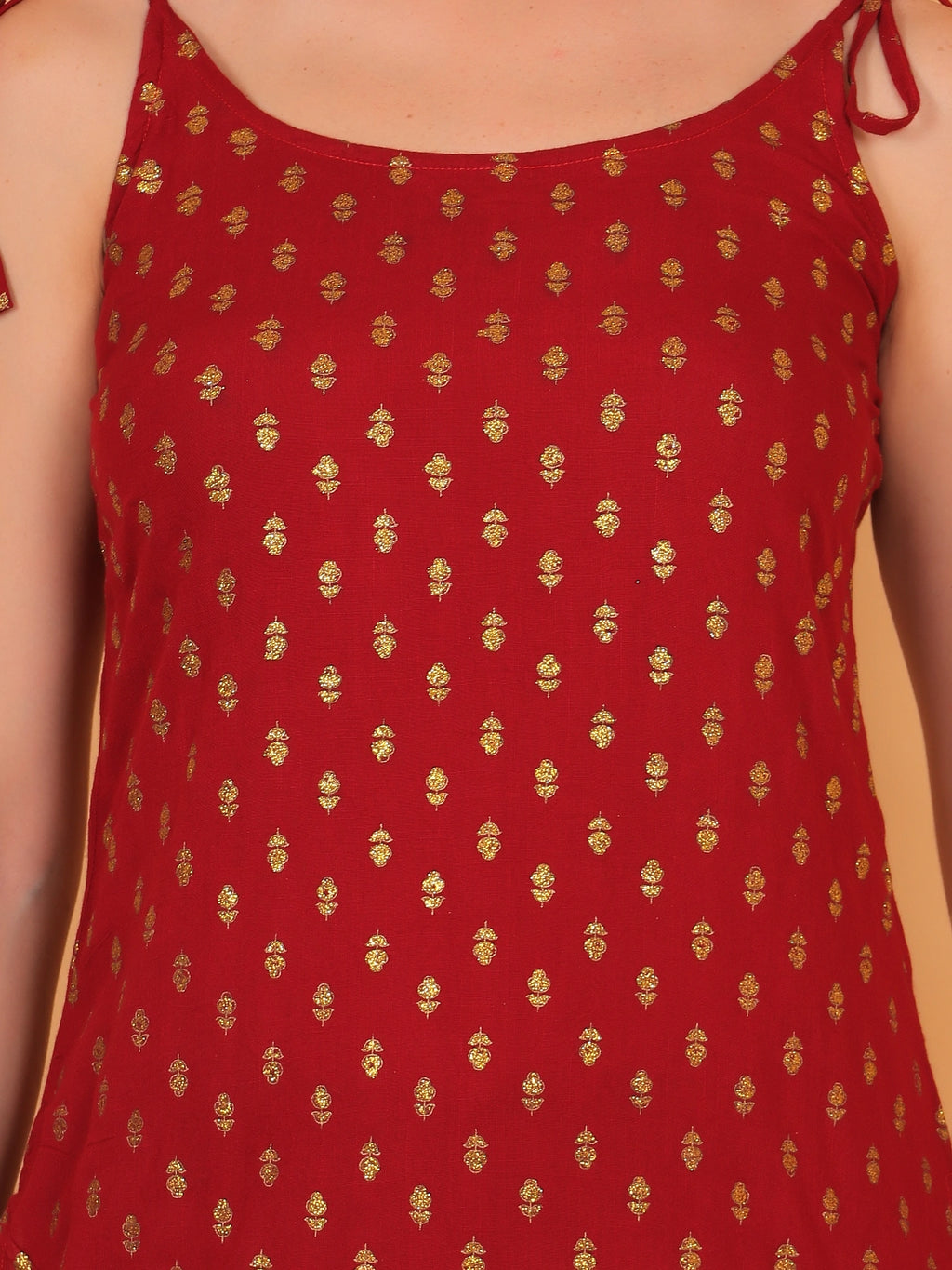 Red sleeveless short kurti with adjustable tie-up shoulder straps paired with light blue jeans.