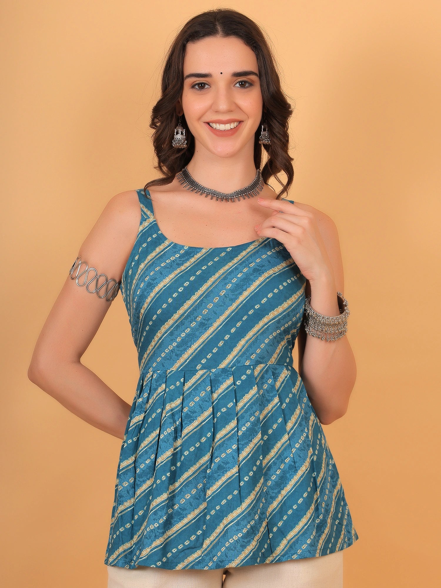 Front view of a model styling a blue shibori printed short kurti for women paired with beige pants, an ethnic casual and lightweight summer outfit.