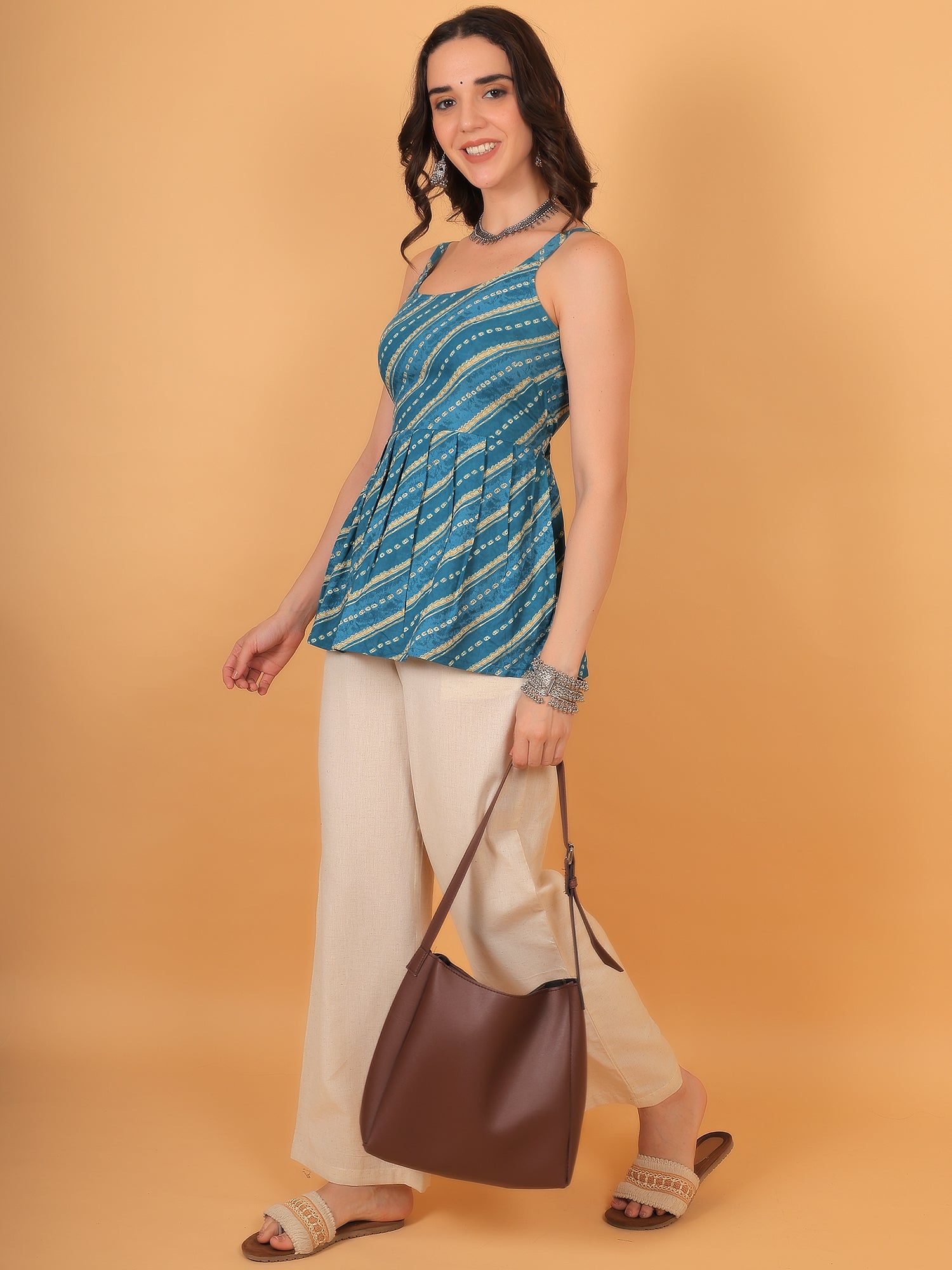 Woman wearing turquoise indo-western short kurti paired with beige wide-leg pants and tote bag.