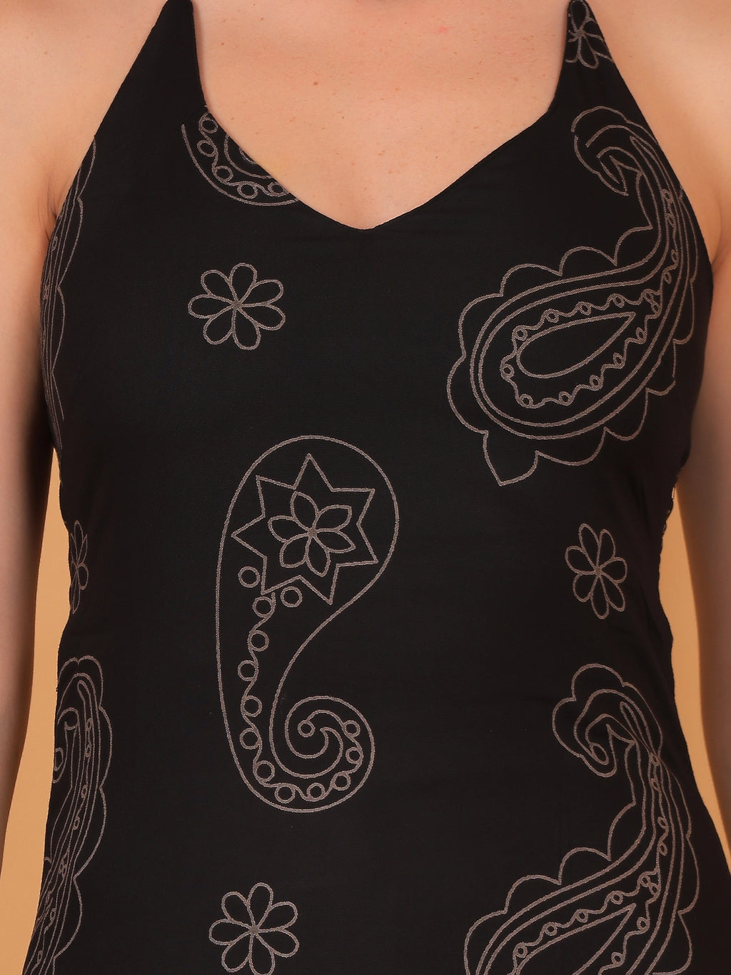 A modern black sleeveless halter-neck kurti with white paisley details paired with casual trousers for a trendy college or festive look.

