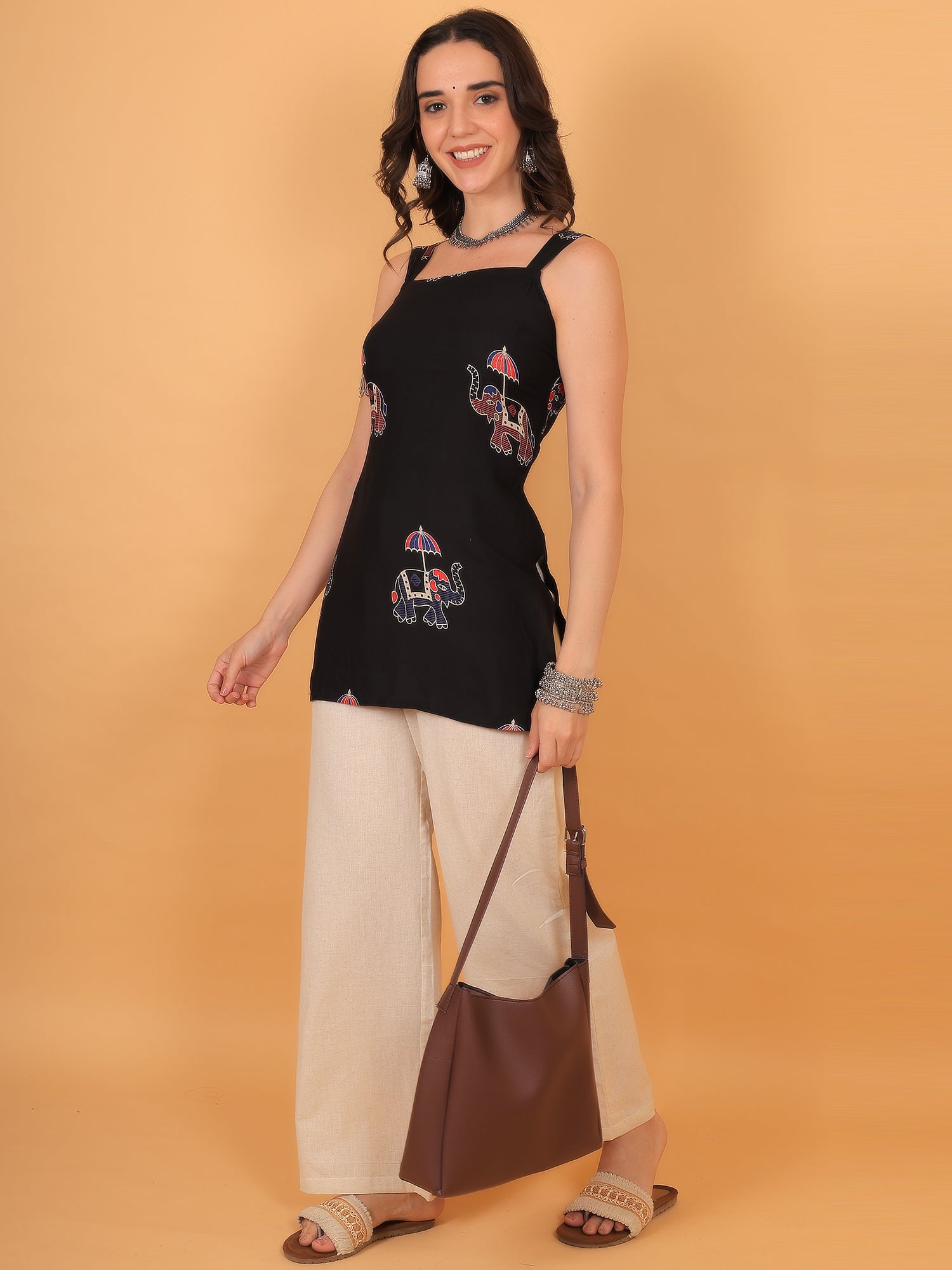 Woman wearing black Indo-western sleeveless tunic paired with beige wide-leg pants