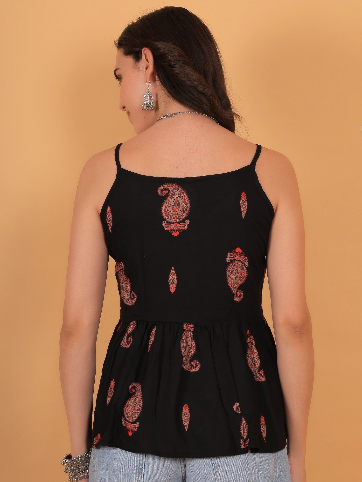 Rear profile view of the ZUACC Indira Fit & Flare Ethnic Top, showcasing the clean sleeveless shoulder cut and the continuous golden motif print across the back of the black rayon fabric.