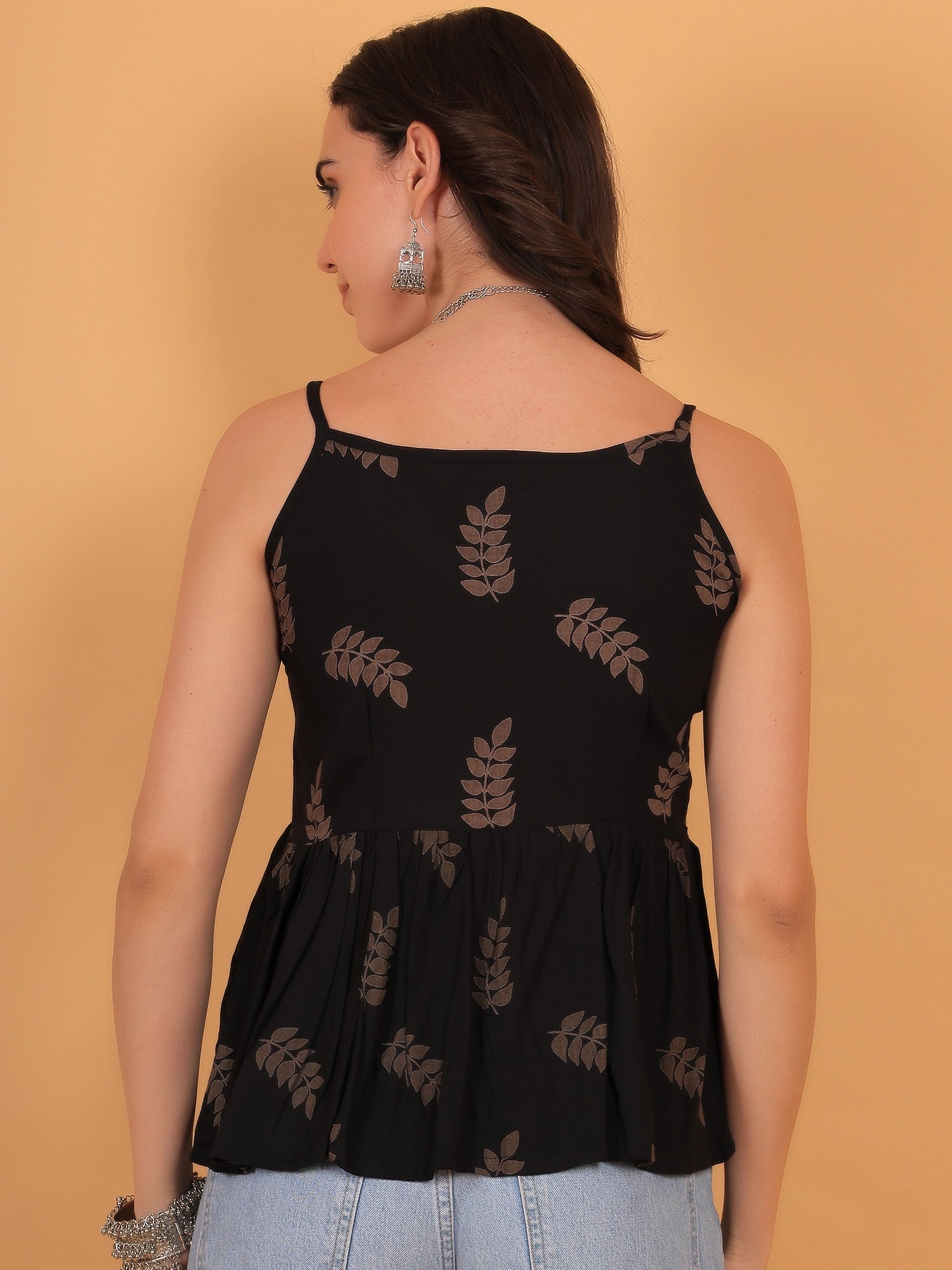 Rear profile view of the ZUACC Vanya fit and flare ethnic top, showcasing the clean sleeveless shoulder cut and the continuous brown leaf print pattern across the back of the black rayon fabric.