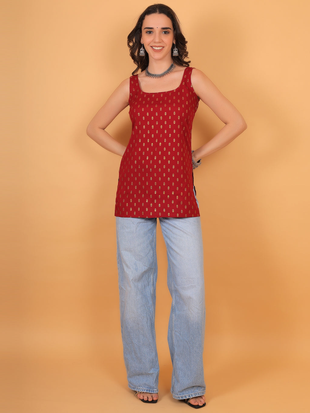 Woman wearing straight cut red festive ethnic top paired with light wash jeans.