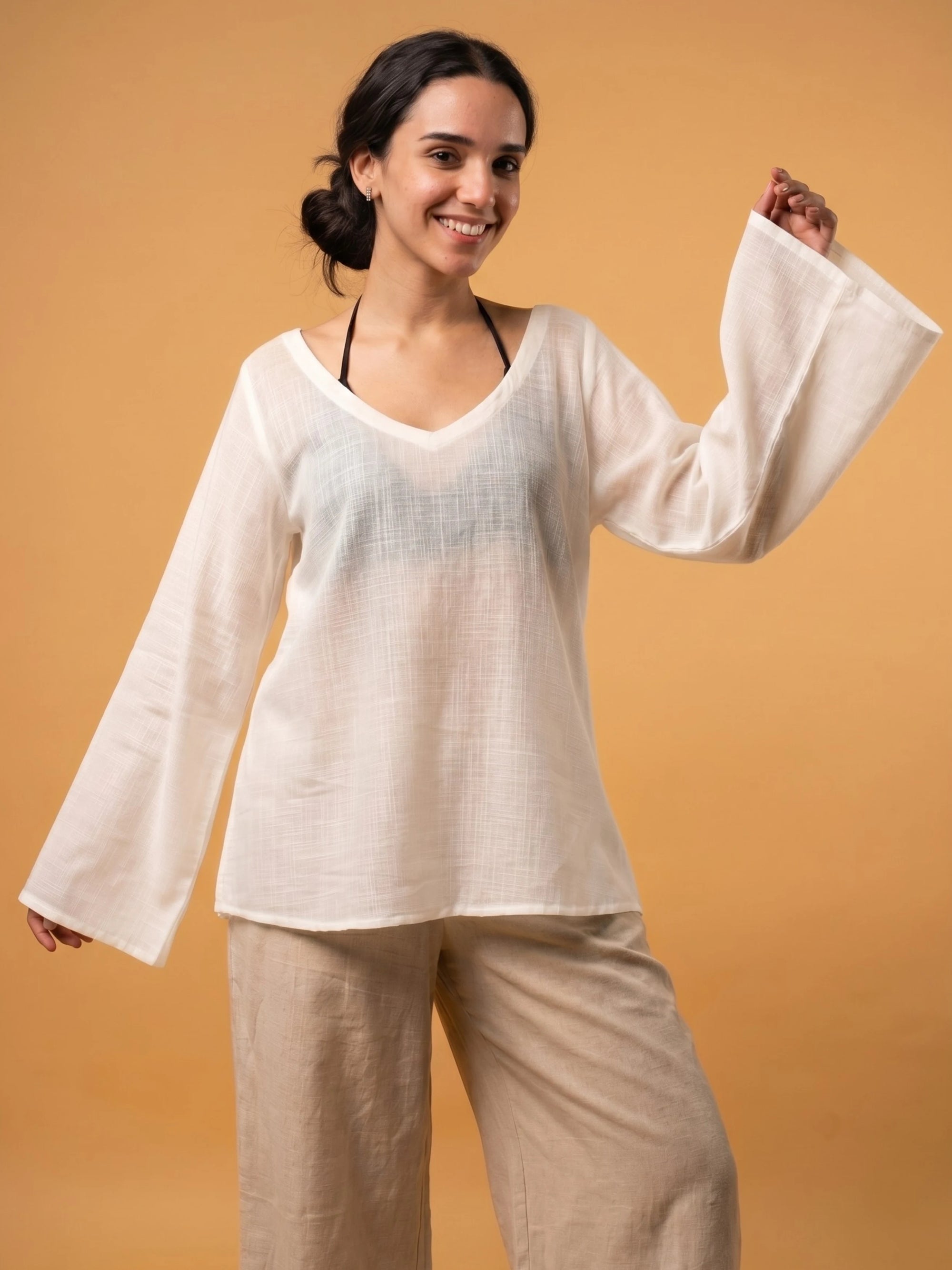Off-white Zora sheer cover up worn as a loose-fit lightweight jacket over a western top and trousers.