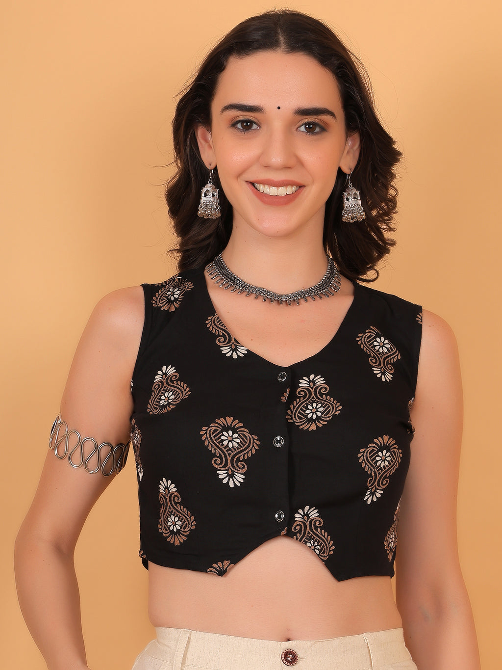 Model smiling in Avira black sleeveless ethnic vest top with beige paisley print.