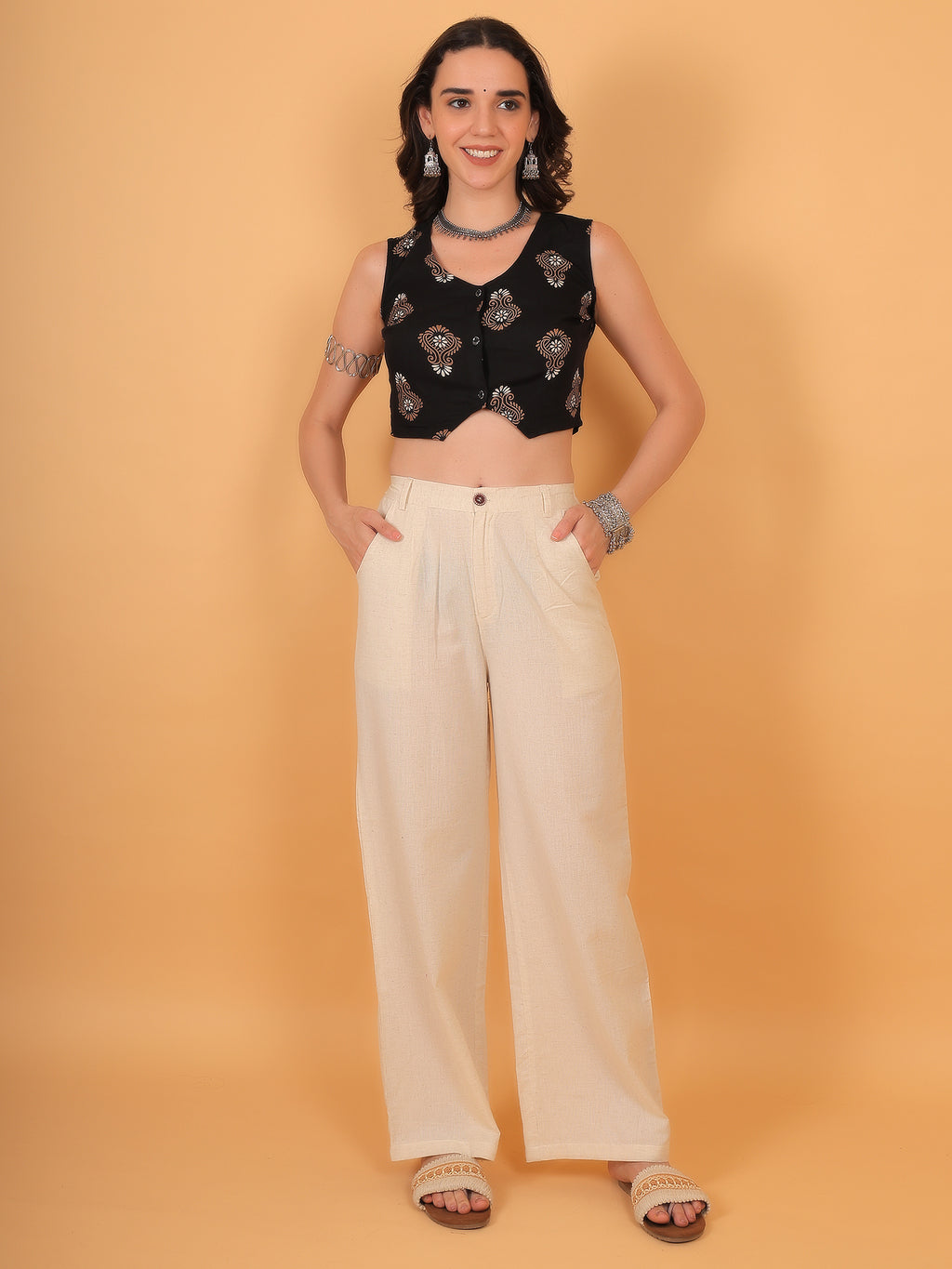 Woman wearing V-neck black crop waistcoat paired with beige linen trousers.