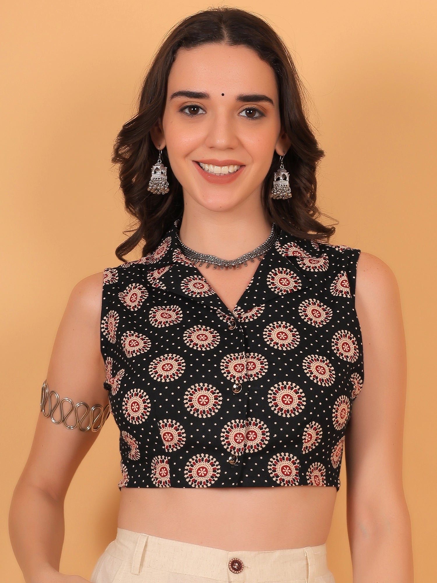 Front view fit inspo of a women black sleeveless crop shirt featuring a regular collar and a vibrant red and white chakra print pattern.