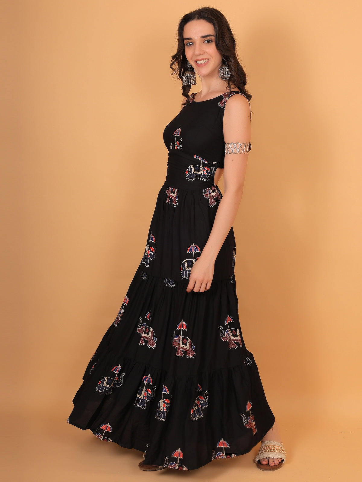 Front view fit inspo of a women black gown featuring a flared tiered skirt and a traditional elephant motif print, perfect for modern Indo Western styling.