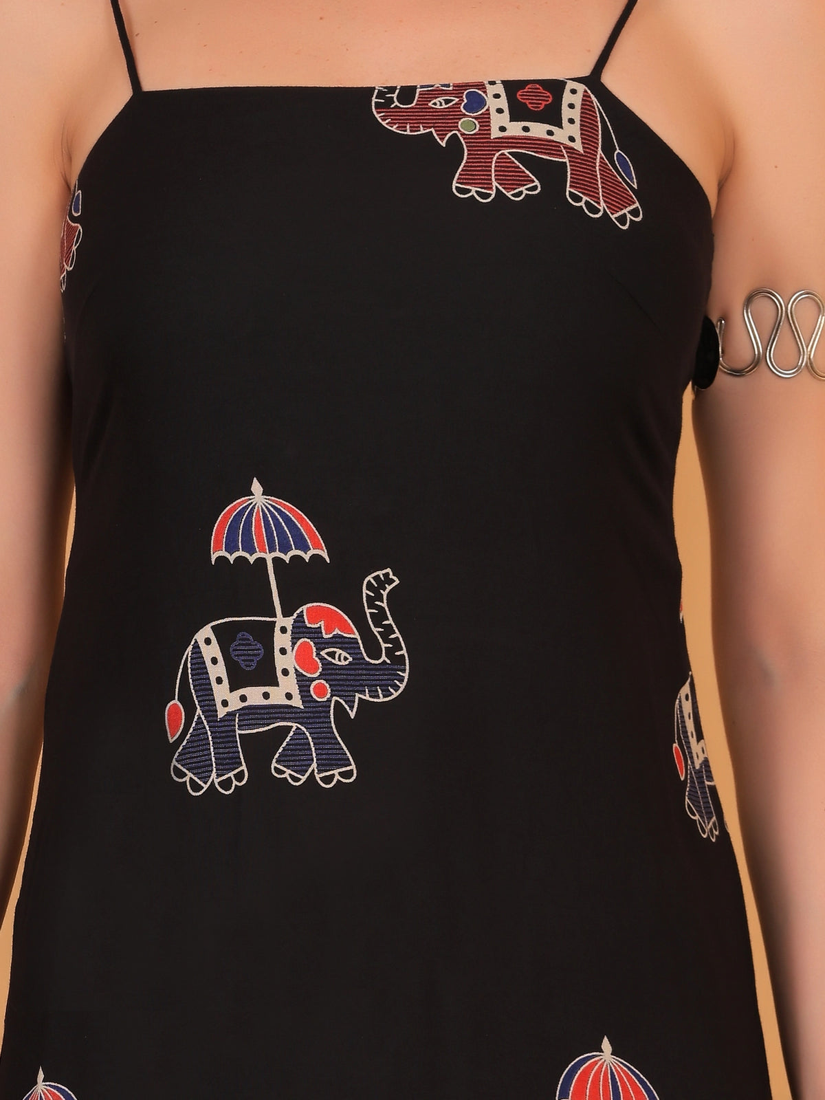 Close-up texture of the breathable fabric and detailed ethnic elephant prints on a black sleeveless indo western dress.