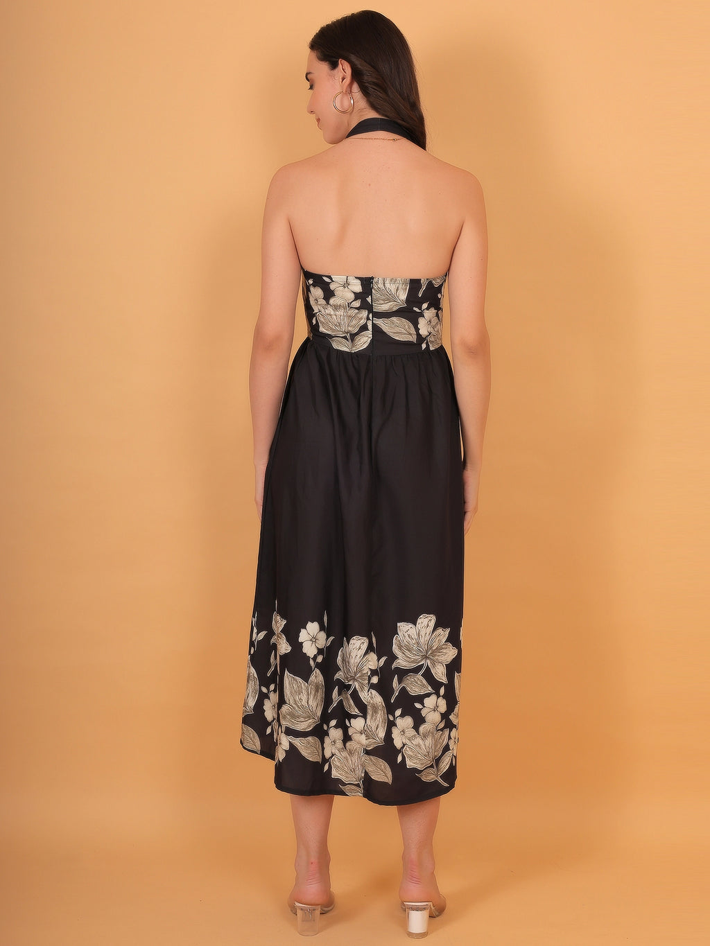 Back view styling of the elegant black halter neck design and waist cut-out detail on a flowy floral print dress.