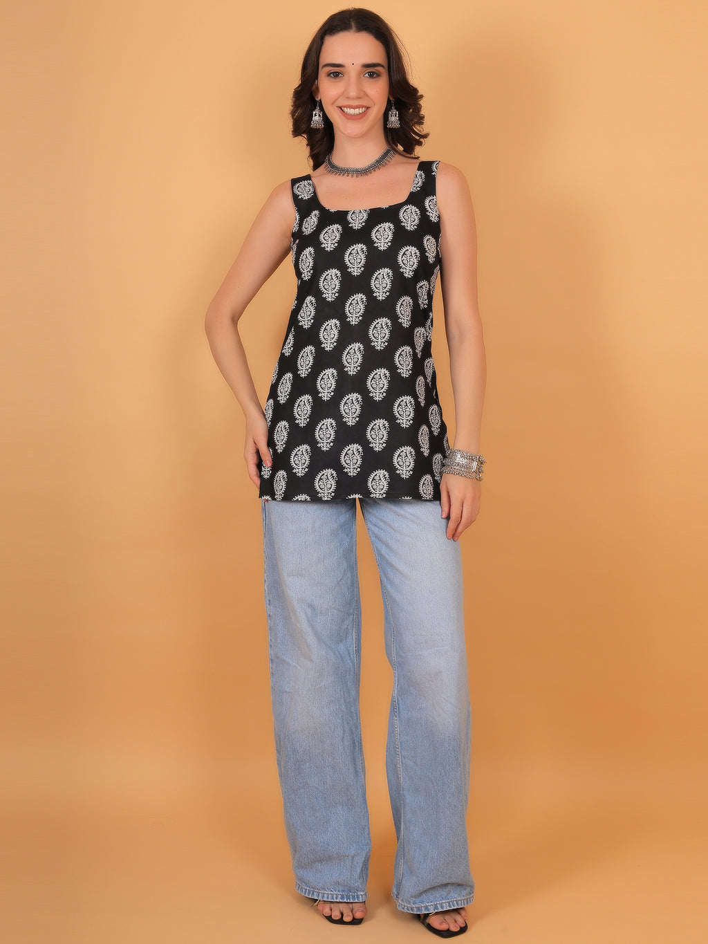 Woman wearing straight cut black ethnic top paired with wide-leg blue jeans.